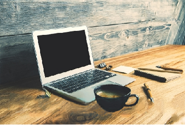 Laptop und Tasse auf Holztisch