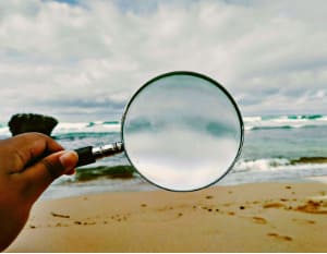 Symbolisch für die Wahrheit des Klienten; Blick durch die Lupe auf das Meer
